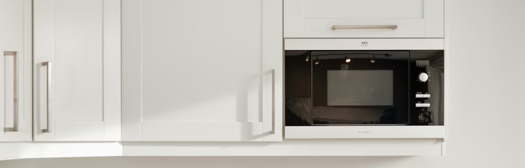 Vit köksinredning med inbyggd svart mikrovågsugn.